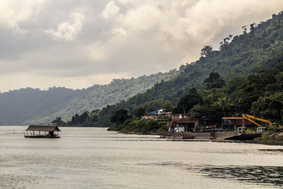 Scenic view of houses by trees and mountains against sky