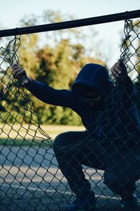 Man seen through chainlink fence against sky