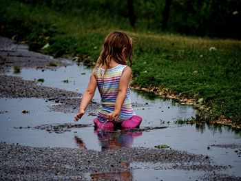 Side view of young girl playing in puddle during rain