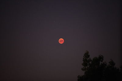 Low angle view of red moon against sky at night