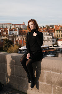 Portrait of smiling young woman against building in city