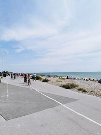 People on road by sea against sky