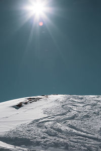 Scenic view of snow on sunny day against sky