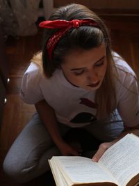 High angle view of woman reading book while sitting at home