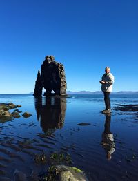 Man standing by sea against clear blue sky