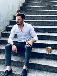 Young man looking away while sitting on staircase