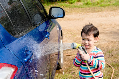 Portrait of cute boy washing car outdoors