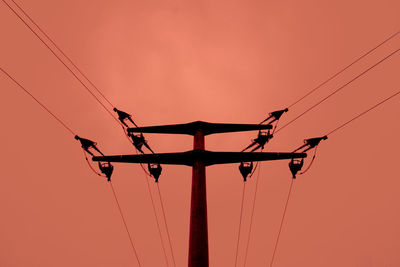 Low angle view of silhouette electricity pylon against sky during sunset