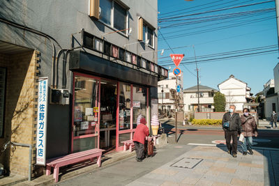 Rear view of people walking on street amidst buildings in city