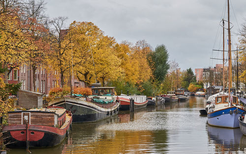 Boats moored in canal against sky during autumn