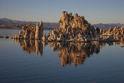 Reflection of rocks in lake against sky