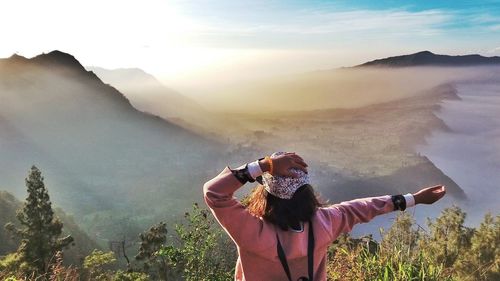 Rear view of woman standing with mountains in background