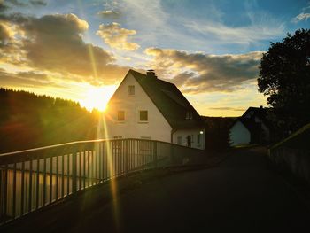 Bridge amidst buildings against sky during sunset