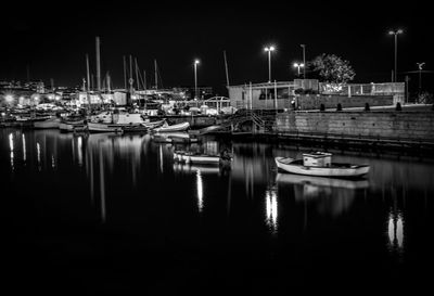 Boats moored at harbor against sky at night