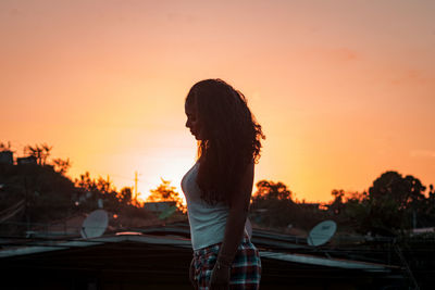 Rear view of woman standing against orange sky