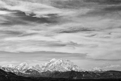 Scenic view of snowcapped mountains against cloudy sky