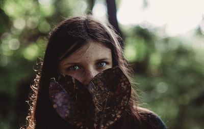 Close-up portrait of girl with dry leaves