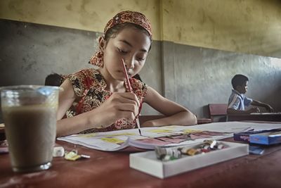 Full length portrait of a smiling girl sitting on table