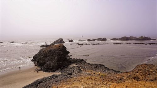 Rocks on beach against clear sky