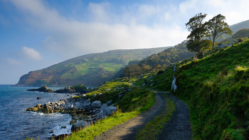 Scenic view of road by sea against sky