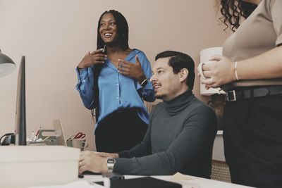 Smiling male entrepreneur sitting by female colleagues at office