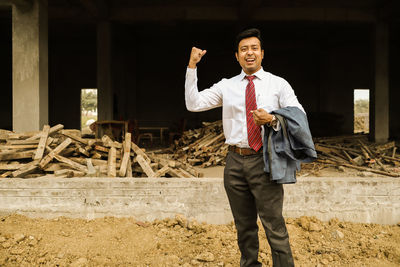 Portrait of a smiling young man standing at construction site