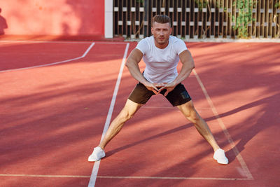 Full length of young woman exercising on field