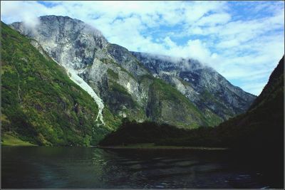 Scenic view of lake by mountains against sky