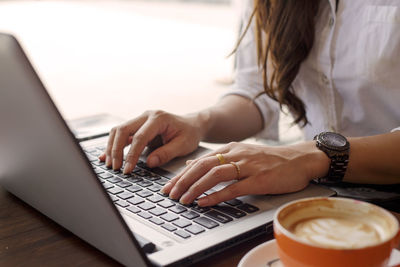 Midsection of businesswoman using laptop in office