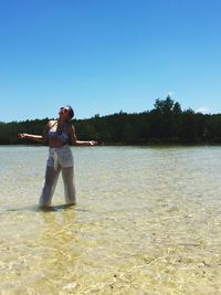 Woman standing in sea against clear sky