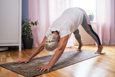 Side view of man sitting on hardwood floor at home