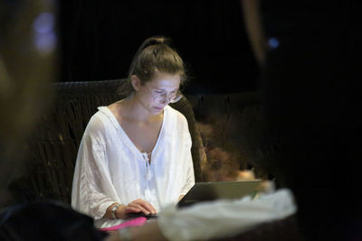 Woman looking at camera while sitting on mobile phone