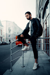 Side view of young man standing on street in city