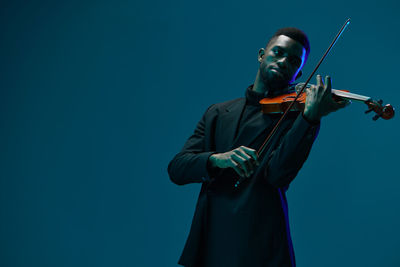 Man holding violin against blue background