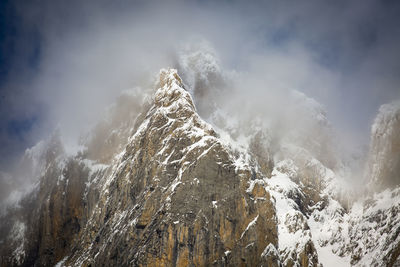 Low angle view of snow capped mountains against sky