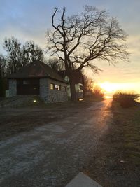 Empty road along buildings at sunset