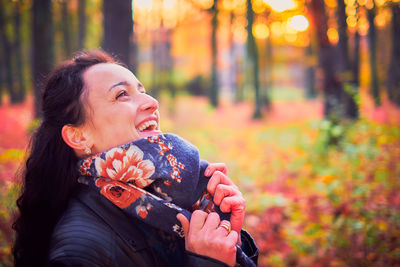 Young woman looking away while standing on tree during autumn