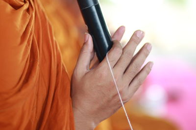 Midsection of monk holding mice and thread during prayer