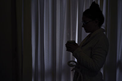 Man holding smart phone while standing in mirror