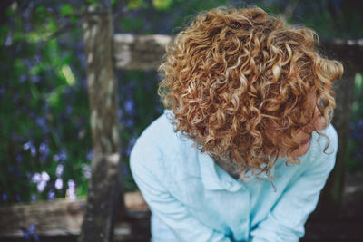 Close-up of woman with curly short hair sitting on bench