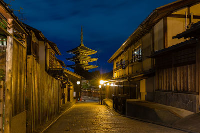 Street amidst illuminated buildings against sky at dusk