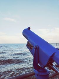 Close-up of coin-operated binoculars on sea against sky