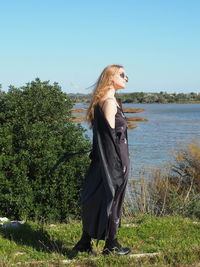 Woman standing by plants against sky