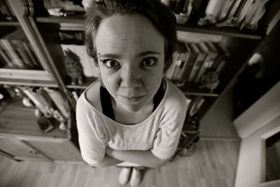 Close-up portrait of woman standing by bookshelf