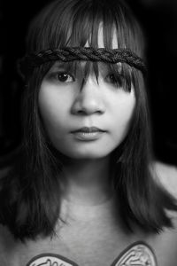 Portrait of young woman sitting against black background