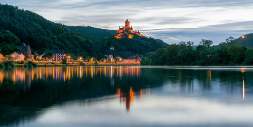 Scenic view of cochem imperial castle on mountain reflecting in river at dusk