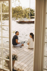 Mature couple talking while working at patio seen through open door of holiday villa