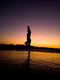 Silhouette woman standing on beach during sunset
