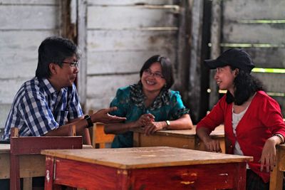 Happy friends discussing while sitting at table