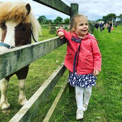 Full length of girl standing by horse at ranch